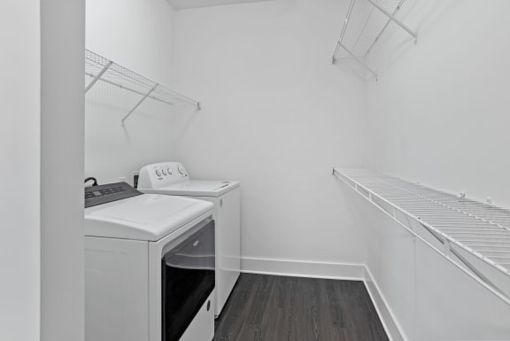 a washer and dryer in a white laundry room with white walls and wood