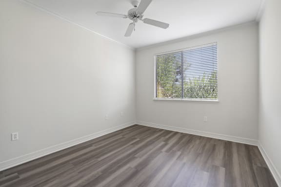 an empty room with a window and a ceiling fan