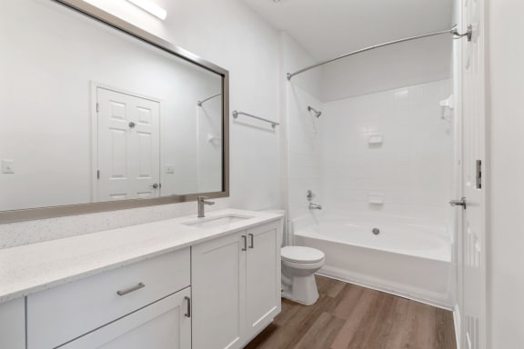a white bathroom with a large mirror and a shower and a toilet