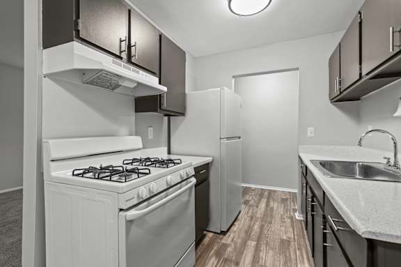 A kitchen with a stove, refrigerator, and sink.