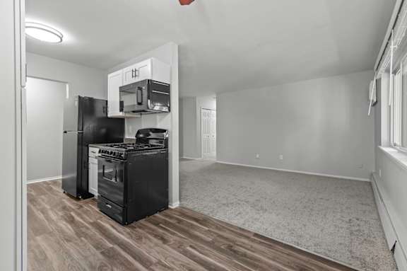 A kitchen with black appliances and wood flooring.