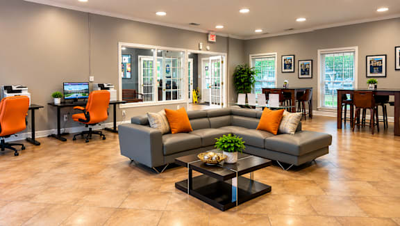 A spacious living room with a grey sofa, orange chairs, and a coffee table.