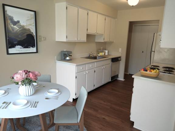 A kitchen with a table set for two with a vase of pink flowers on it.