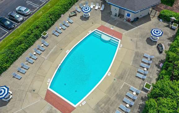 a large swimming pool with chaise lounge chairs and a building in the background