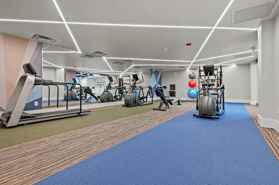 A gym with a blue mat in the foreground and various exercise equipment.
