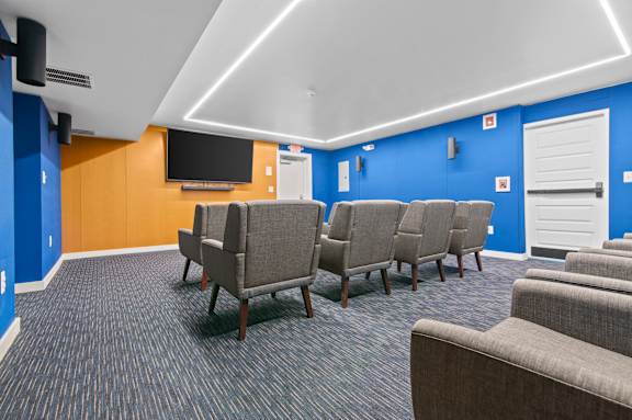 A room with blue walls and a row of grey chairs.