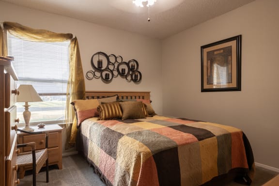 Bedroom in a one-bedroom model unit at The Lakes, featuring a queen-size bed.
