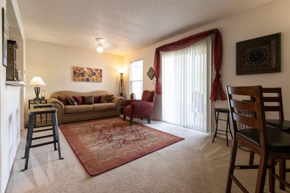 Living room view showcasing a sliding door that opens to a patio, in a one-bedroom townhome model unit at The Lakes.