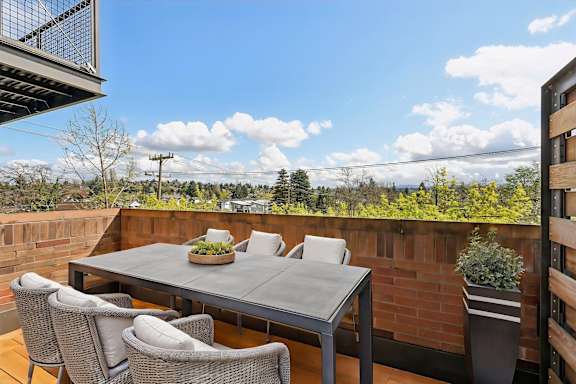 A table with chairs on a balcony with a view of the sky.