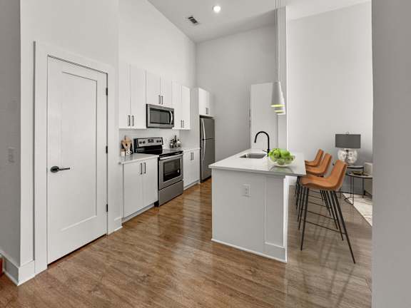 A kitchen with white cabinets and a wooden floor.