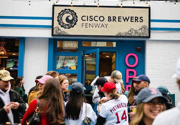 A group of people are standing in front of a Cisco Brewers Fenway store.