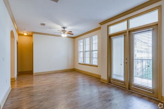 an empty living room with windows and a ceiling fan