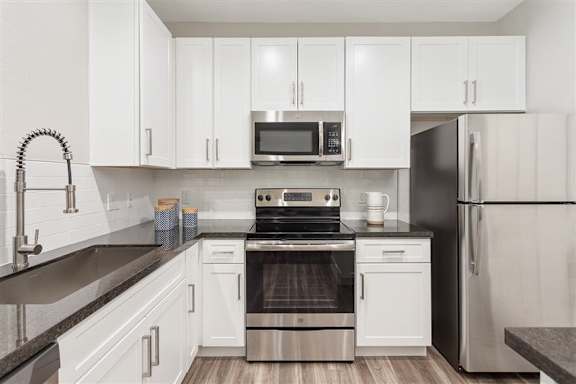 A modern kitchen with white cabinets and stainless steel appliances.