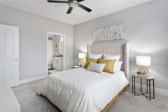 A bedroom with a large bed, a ceiling fan, and a nightstand with a lamp.