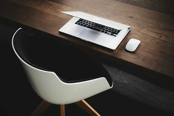 A laptop and mouse are on a wooden desk.