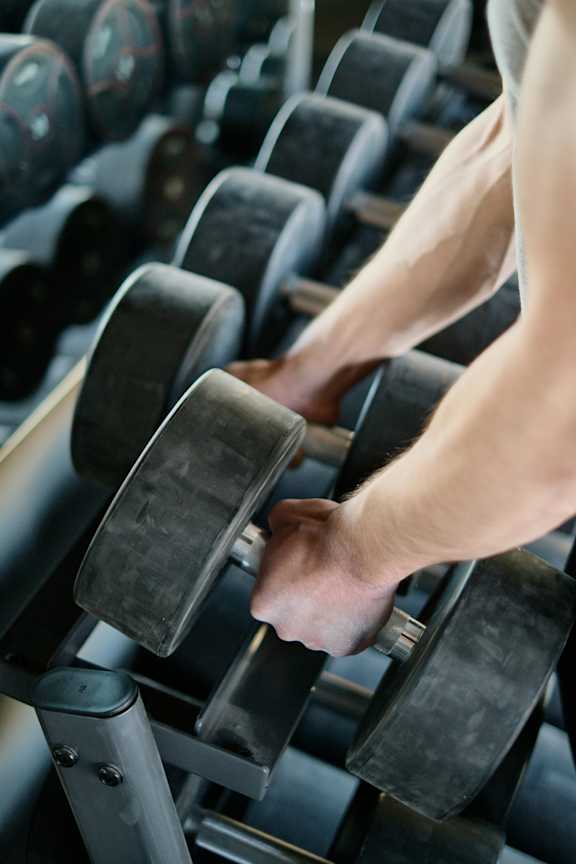 A person lifting dumbbells in a gym.