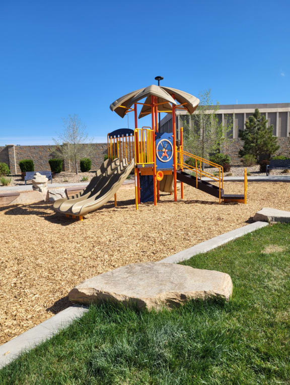 A playground with a yellow and blue structure and a slide.