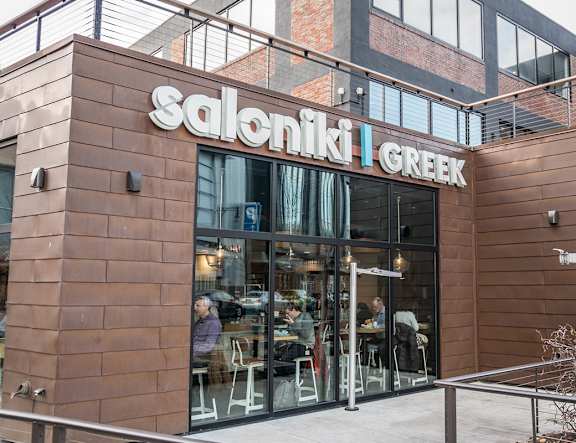 Saloniki Greek restaurant with people sitting at tables outside.
