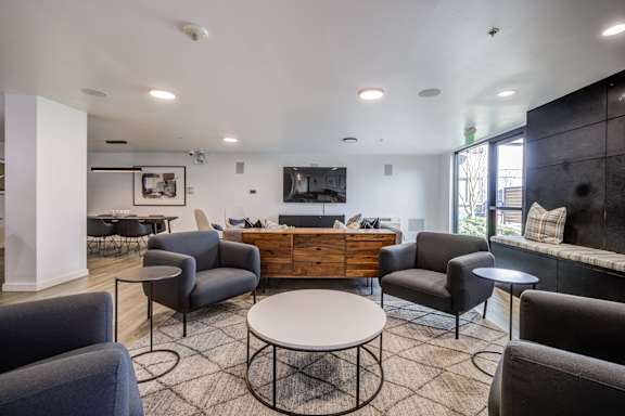 A living room with a white table surrounded by grey chairs.