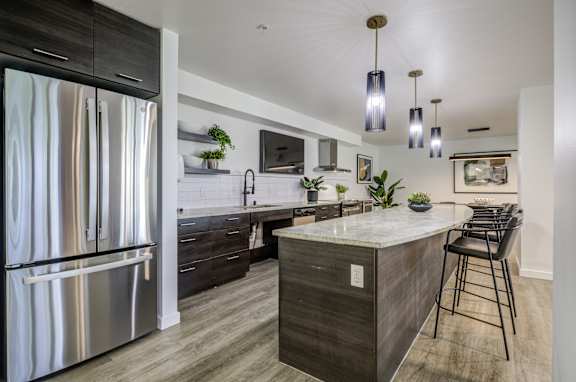 A modern kitchen with a marble countertop and stainless steel appliances.