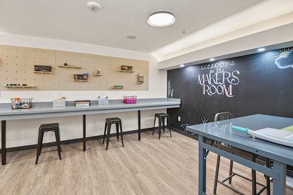 A room with a chalkboard wall and a long table with stools.
