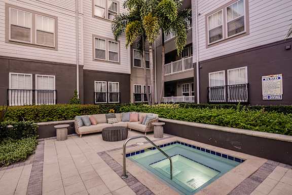 A pool surrounded by a patio and a building.