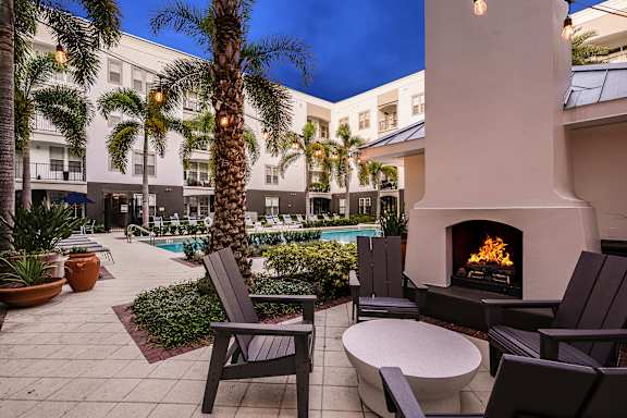 A patio with a fireplace, chairs, and a table.