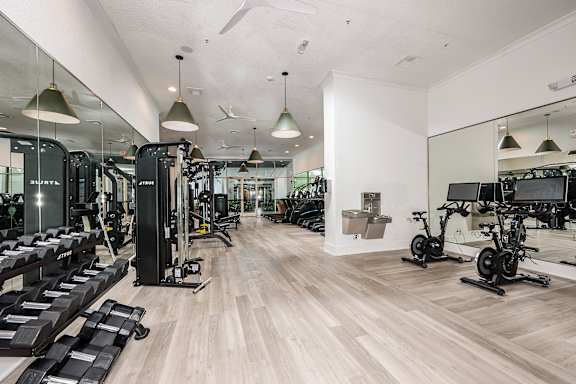 A gym with a variety of equipment including treadmills, weights, and exercise bikes.