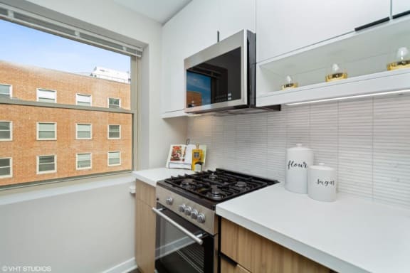 a kitchen with a stove top oven next to a window at Carver and Slowe Apartments, Washington