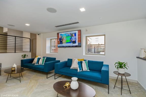 a living room with blue couches and a flat screen tv at Carver and Slowe Apartments, Washington, DC