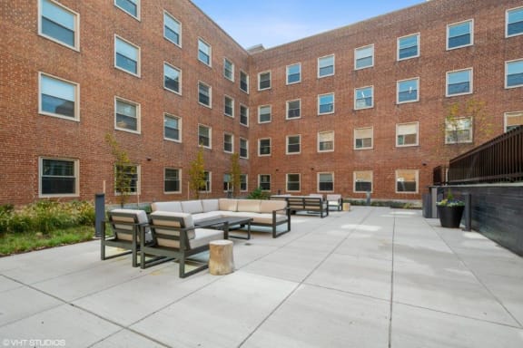a courtyard with couches and tables in front of a brick building at Carver and Slowe Apartments, Washington