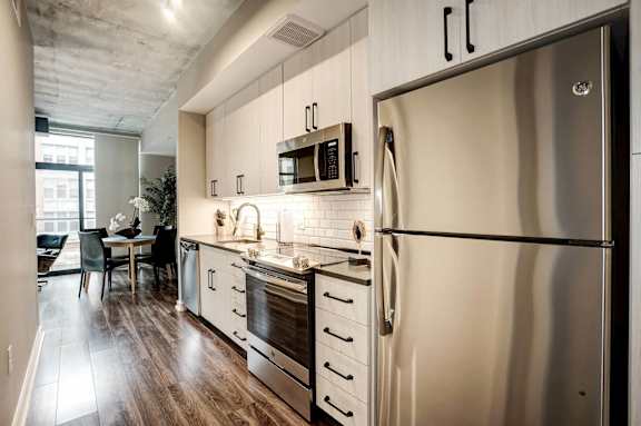 a kitchen with stainless steel appliances and white cabinets at Coda on H Apartments, Washington