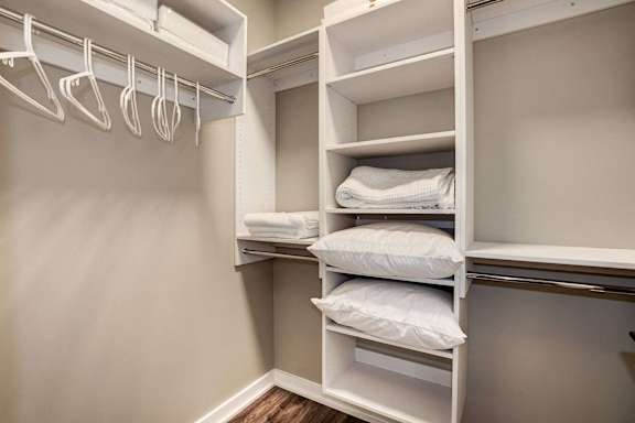 a walk in closet with white shelves and pillows at Coda on H Apartments, Washington, District of Columbia