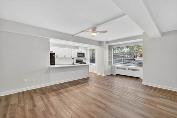 A room with a ceiling fan and wooden flooring.