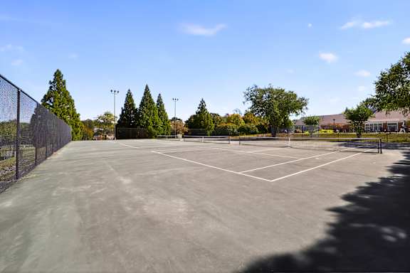 A tennis court surrounded by a fence and trees.