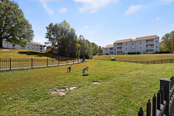 A grassy field with a fence and a building in the background.