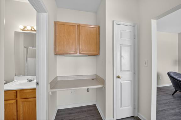A small bathroom with a white sink and wooden cabinets.