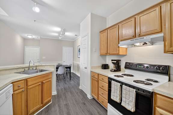 A kitchen with wooden cabinets and a white stove top oven.