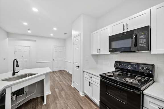 A kitchen with white cabinets and a black stove top oven.