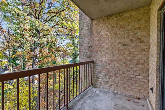 A balcony with a brick wall and a metal railing.