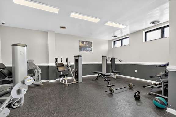 A gym with a variety of equipment including weights and a bench.