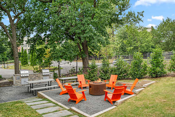 a group of orange chairs around a fire pit in a park