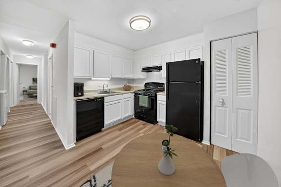 A kitchen with black appliances and white cabinets.