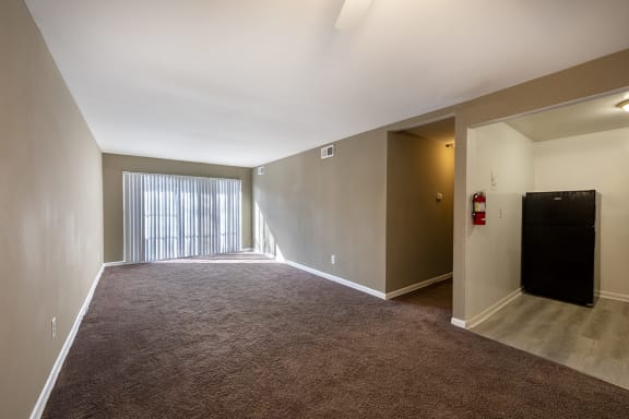 an empty living room with a large window and a door to a balcony