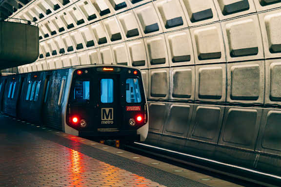 A black train with the Metro logo on the back is on a track.
