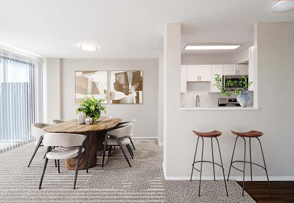 A modern dining room with a round wooden table and white chairs.