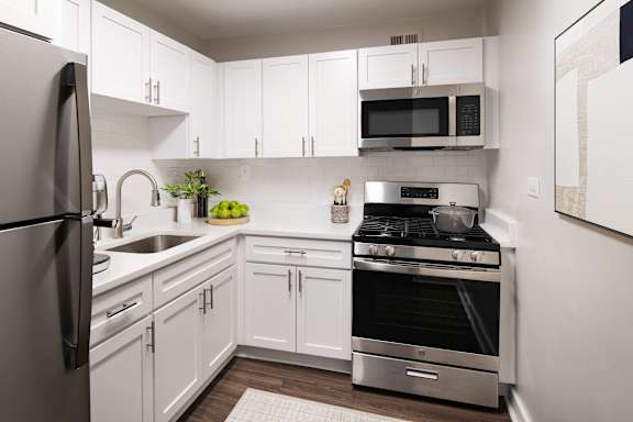 A modern kitchen with white cabinets and stainless steel appliances.