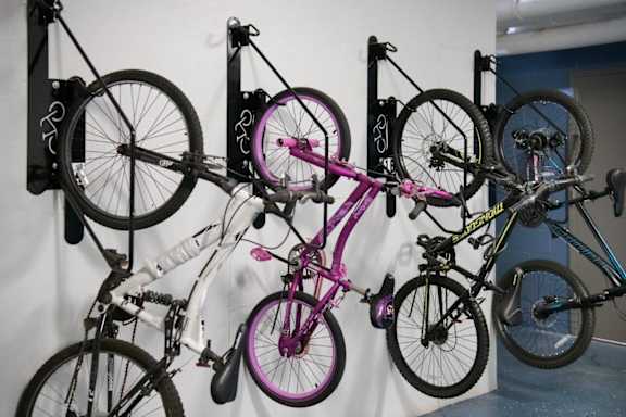 A collection of bicycles are hanging on a wall.
