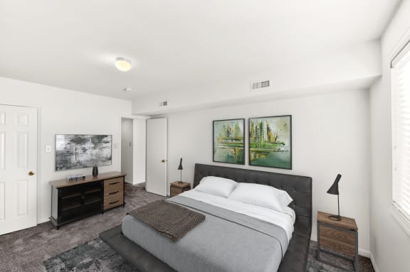 a white bedroom with a bed and two paintings on the wall