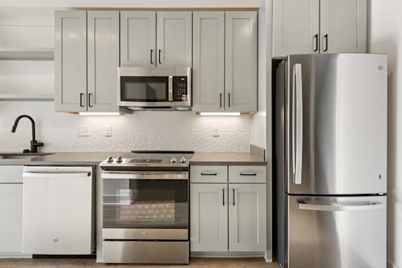 A modern kitchen with a refrigerator, oven, and microwave.